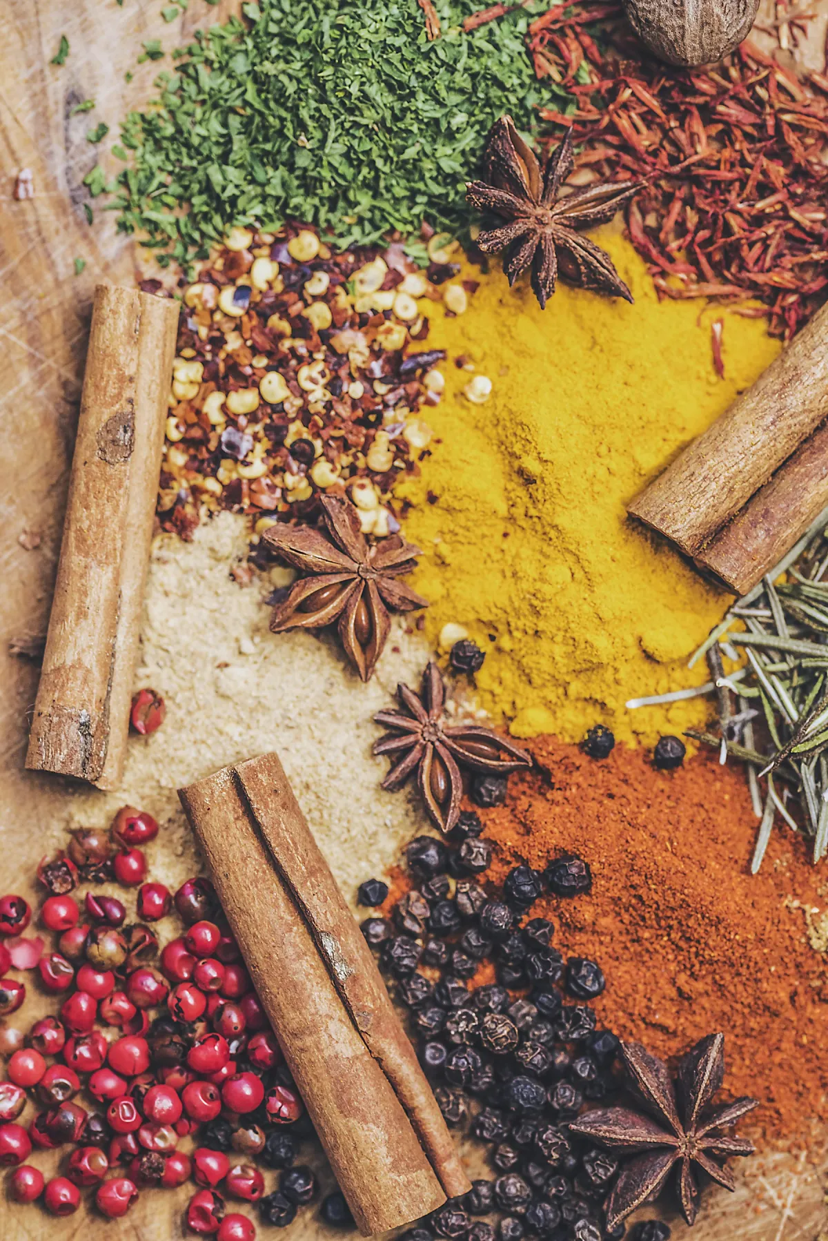 Cinnamon, star anise, peppercorns, herbs, and ground ingredients arranged together